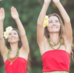 two women dancing Hula with greenery in the background