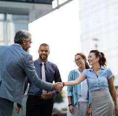 professionals standing outside. Two of them are shaking hands