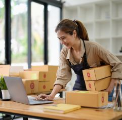 woman holding boxes and looking at the computer