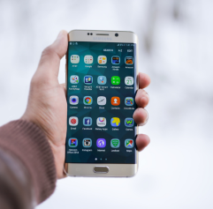 a hand holding a phone showing the home screen of an Android phone