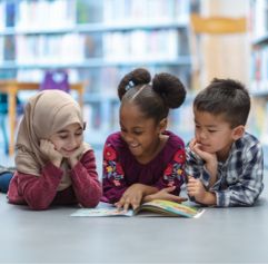 three children reading a book on the floor