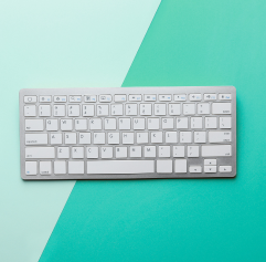 a gray keyboard in the center with a light teal and dark teal solid color background