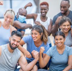 a group of middle-aged adults wearing blue standing together and flexing their arm muscles