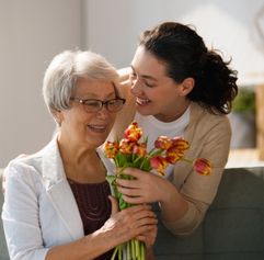 a younger woman giving an older woman flowers