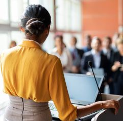working female adult speaking in front of colleagues
