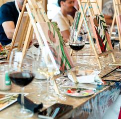 adults painting while drinking wine