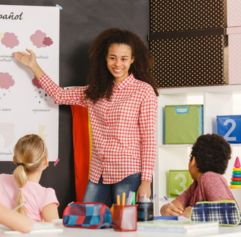 young woman teaching two students Spanish using a dry erase board