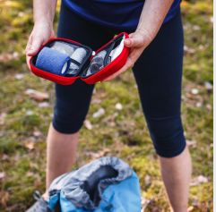 a woman on a grassy field opening a first-aid kit