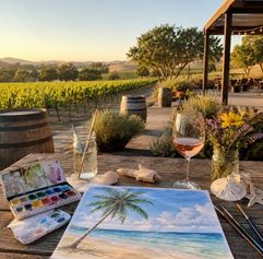 outdoors at a winery with a wine glass and painting of a beach with palm trees and a watercolor pallette on a table AI generated image