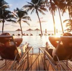 couple sitting my a tropical pool watching the sun set
